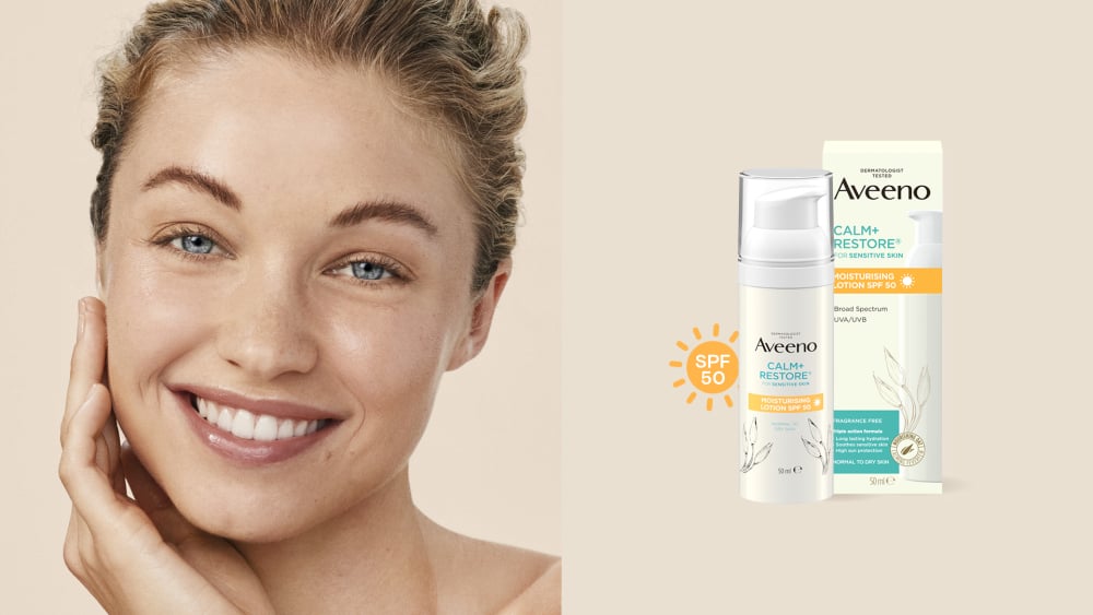 hymyilevä naine ja uusi Aveeno Calm Restore Moisturising Lotion SPF50 kosteusvoide