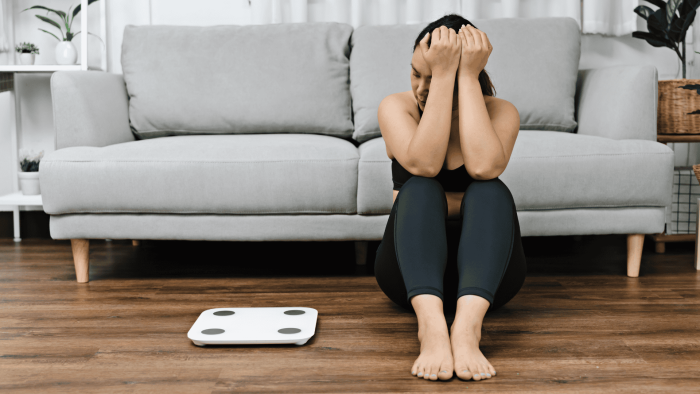 Nainen katsoo sivusilmällä puntaria. Symboliikkaa kysymykselle "miksi paino ei putoa"