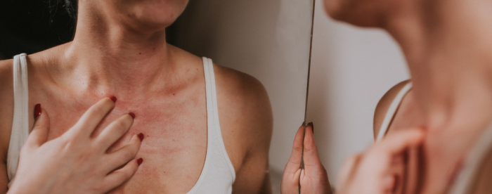 Nainen tutkii kaulan iho peilistä