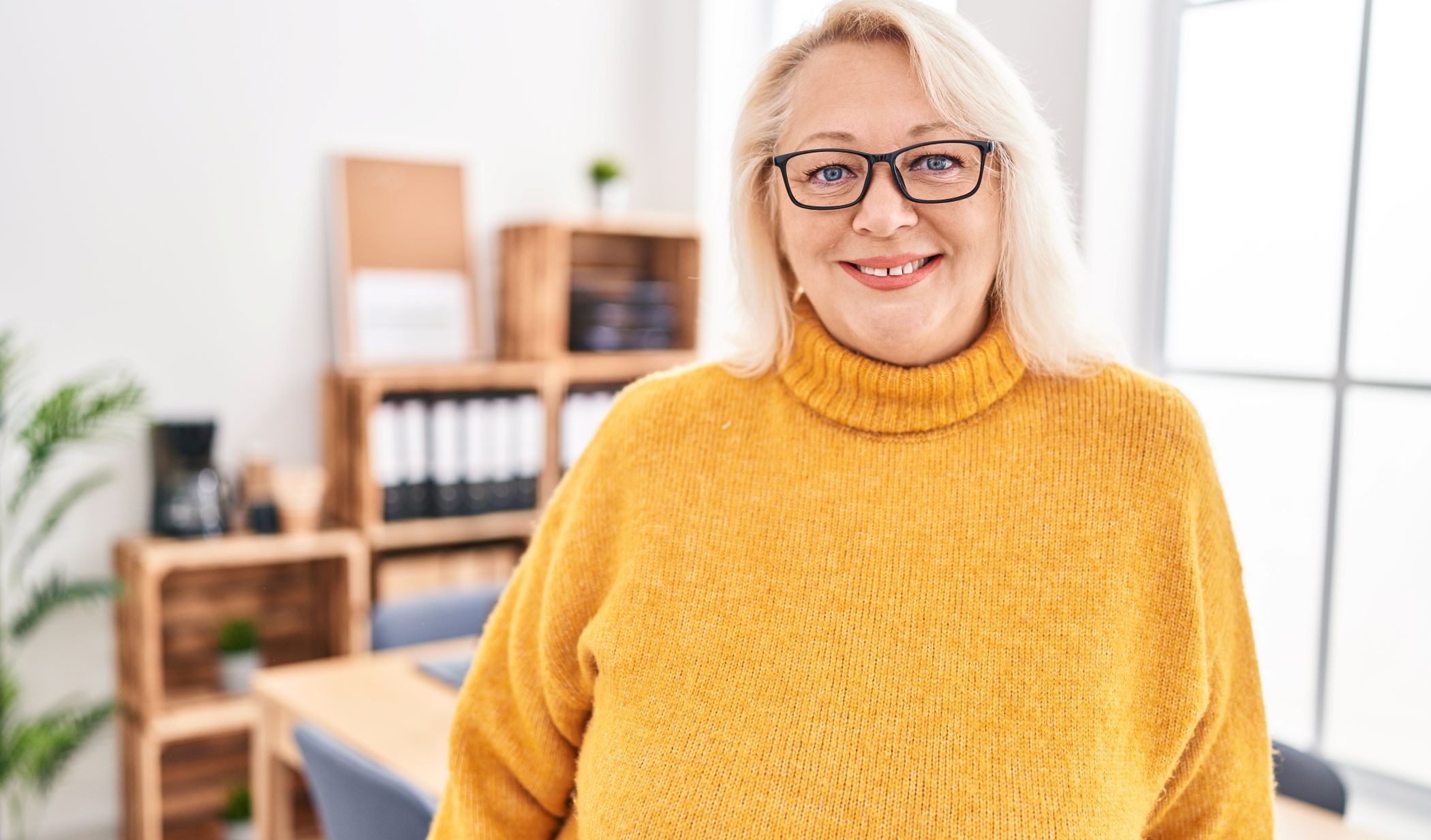 keski-ikäinen nainen kokoushuoneessa keltainen nenule yllään