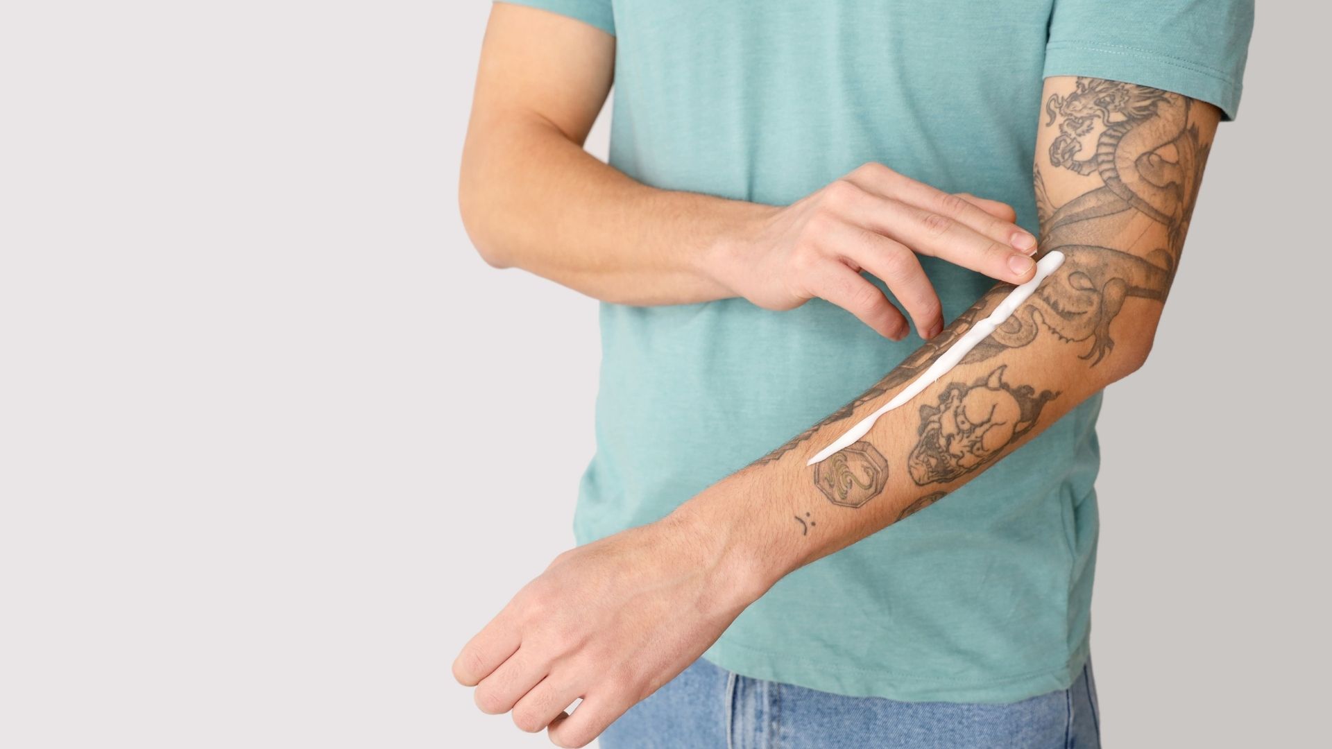 Mies rasvaanmassa tatuointiaan.