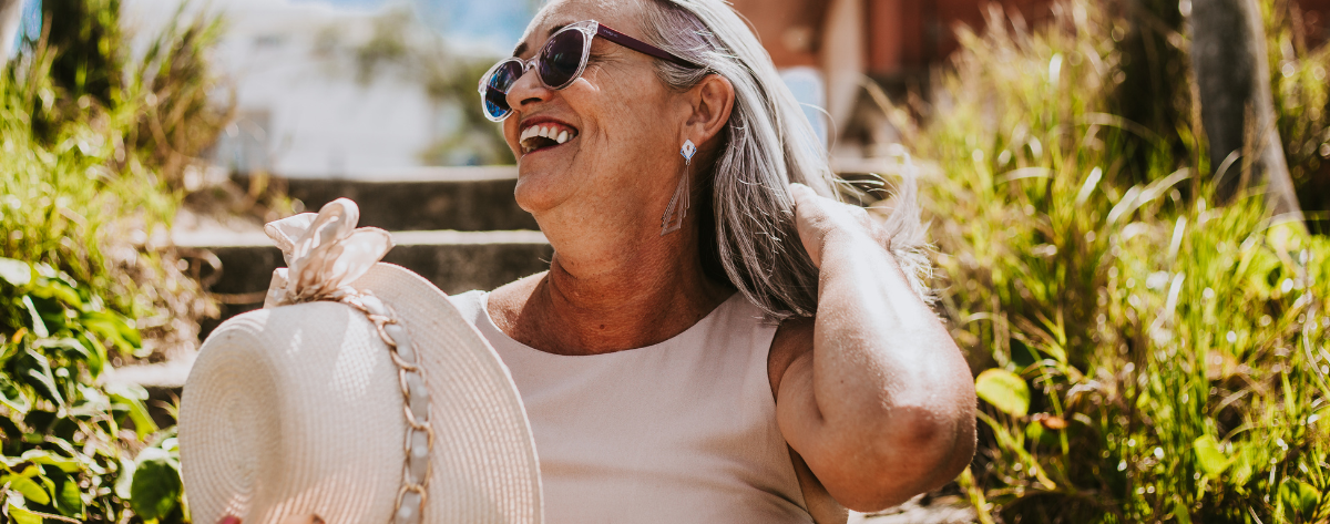 iloinen keski-ikäinen nainen kesällä ulkona lierihattu kädessä