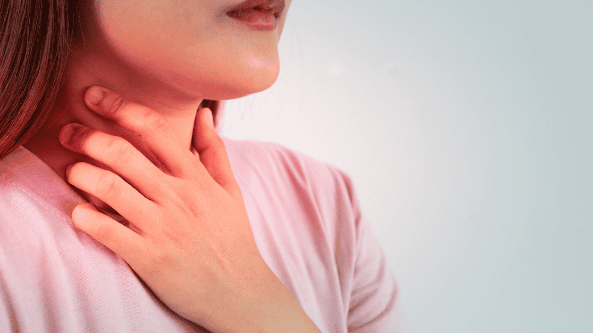 Nainen pitää kättä kipeällä kurkullaan. Kuvituskuva.