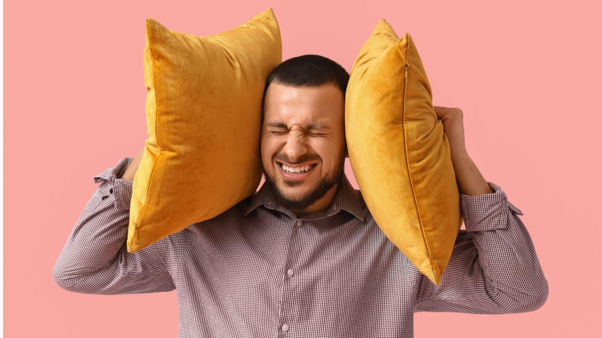 Tinnituksesta kärsivä mies pinkillä taustalla.