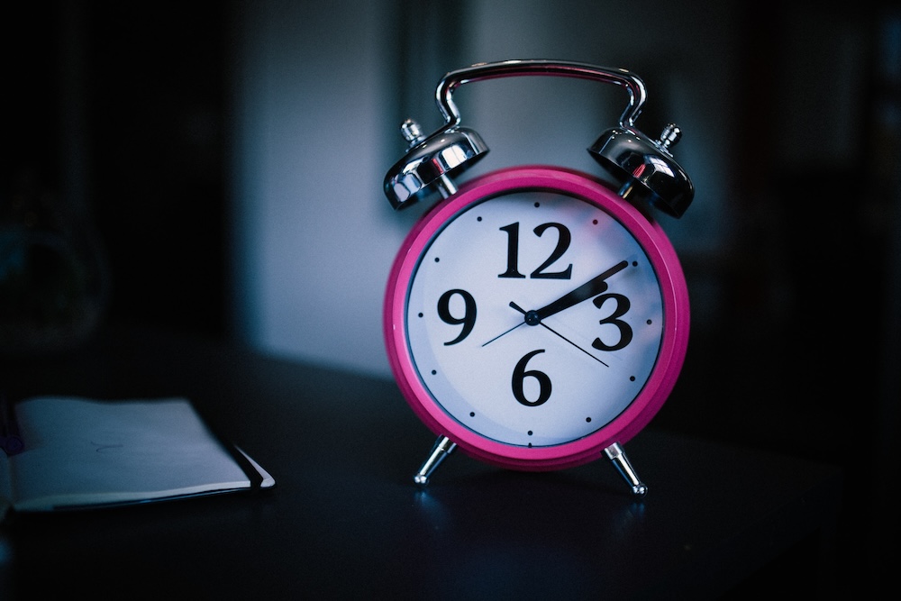 Pinkki herätyskello pimeässä huoneessa kuvastaa unettomuutta. Viisari osoittaa klo 2:10. Unettomuuden hoito kotikonstein, vaikea unettomuus, melatoniini